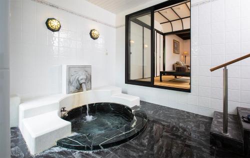 南阿苏村别邸苏庵传统日式旅馆的一间带浴缸、水槽和镜子的浴室