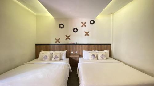 日惹Mawar Asri Hotel的小客房内的两张床,配有白色床单