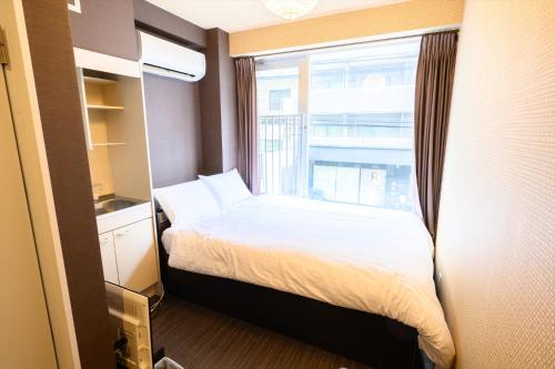 广岛Hiroshima Wabisabi hostel 広島ワビサビ ホステル的一间小卧室,配有床和窗户