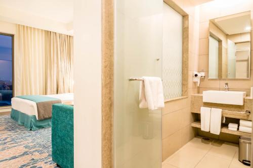 加尔各答Holiday Inn Express Kolkata Airport, an IHG Hotel的酒店客房设有带水槽的浴室和一张床