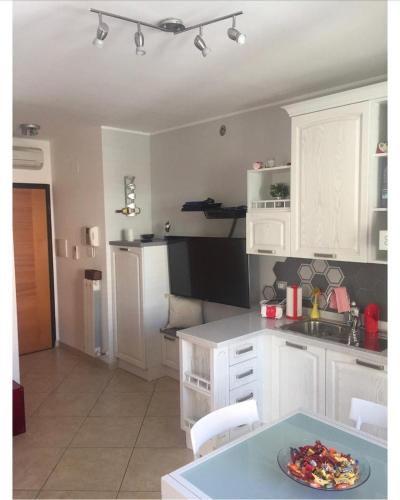 圣贝内代托-德尔特龙托delizioso appartamento的厨房配有白色橱柜和桌子上的盘子