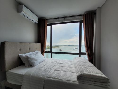 巴淡岛中心Palam Mansion at Apartment One Residence的一间卧室设有一张床和一个大窗户