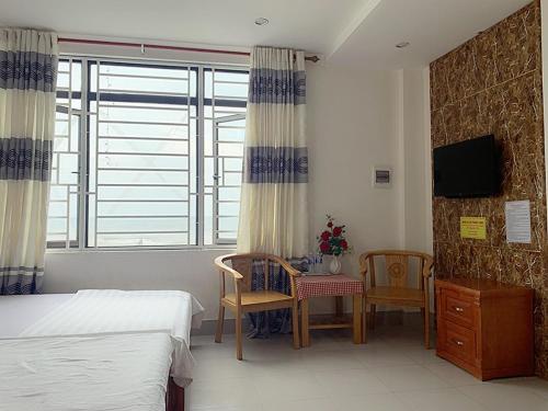 洞海Thăng Long Hotel的卧室配有一张床和一张桌子及椅子