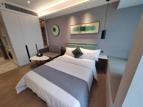 深圳富安酒店公寓（深圳国际会展中心店）的卧室配有一张白色的大床和一张沙发。