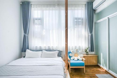 大理大理古城馨宇轩民宿(洱海门店)的一间卧室配有一张床、一把蓝椅和一个窗户。