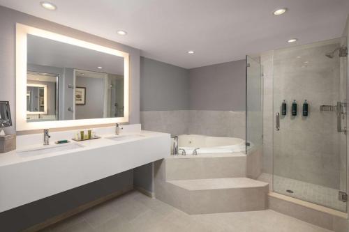 康科德希尔顿康科德酒店的浴室配有2个盥洗盆、淋浴和浴缸。