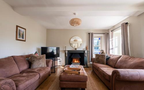 廷特恩Holmleigh cottage的客厅设有2张棕色沙发和壁炉