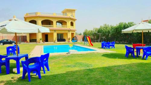 El-Qaṭṭaفيلا للايجار في كمبوند سمر قند的一组蓝色椅子和遮阳伞,位于游泳池旁