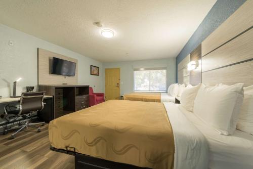 马尼温泉Quality Inn & Suites Manitou Springs at Pikes Peak的酒店客房配有一张床、一张书桌和一台电视。