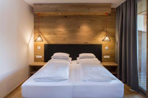 卡奇山口Falkensteiner Aktiv & Familienhotel Cristallo的卧室内的两张床,配有床头板和灯