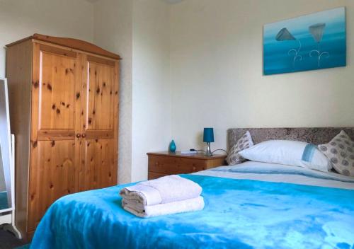 福尔柯克Scardroy Falkirk - 3 Bedroom Apartment的一间卧室配有蓝色的床和毛巾