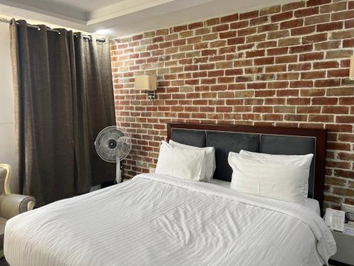卡拉尔哥特Hotel Hayatt Sukkur的一间卧室设有一张带砖墙的大床