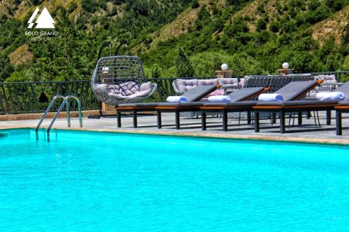 Solo Grand Boshuri Hotel Wellness Resort的游泳池旁设有躺椅和椅子