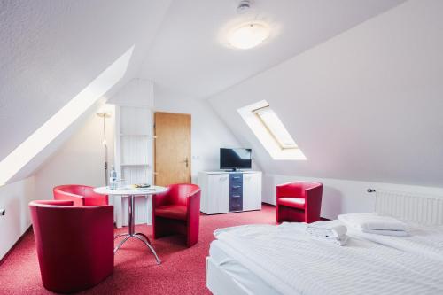 克劳斯多夫Pension Schwalbenhof的一间卧室配有两张床、一张桌子和红色椅子。