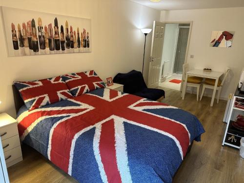 伦敦Modern, Large Independent Room with En-suite Bathroom in Private Owned Apartment的卧室配有红色的白色和蓝色的床和一张桌子