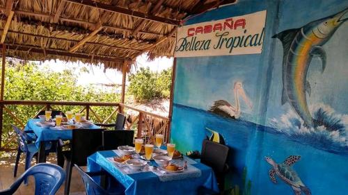 MoñitosHOSTAL BELLEZA TROPICAL的一间设有蓝色桌子和阅读热带海洋厨房标志的餐厅