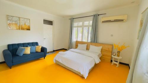 达累斯萨拉姆Gallivanters Hostel的一间卧室配有一张床和一张蓝色的沙发