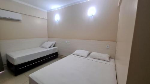 卡达斯诺瓦斯Hotel Spazzio diRoma GRATIS entrada Acqua e Splash Caldas novas的配有白色墙壁的小客房内的两张床