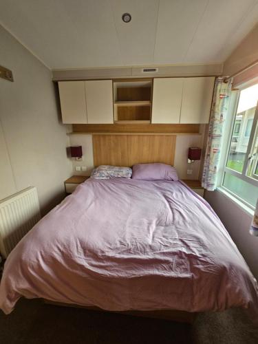 博斯Caravan 4 - Cambrian Coast Caravan Park的一间卧室配有一张带紫色床单的大床