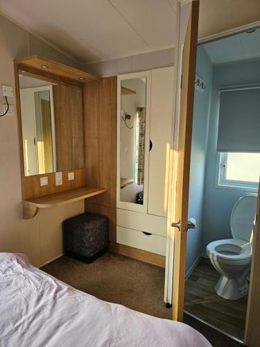 博斯Caravan 4 - Cambrian Coast Caravan Park的一间卧室配有一张床、一个卫生间和一面镜子