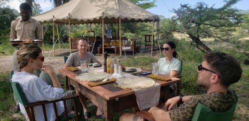 Kwa MhindaMakubi Safari Camp by Isyankisu的一群人坐在木桌旁