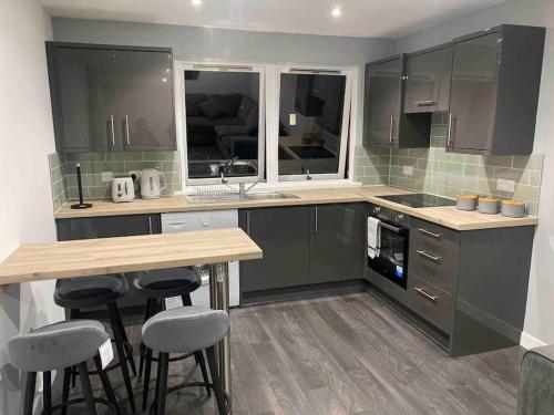 克里夫A modern and homely apartment的厨房配有绿色橱柜、桌子和凳子