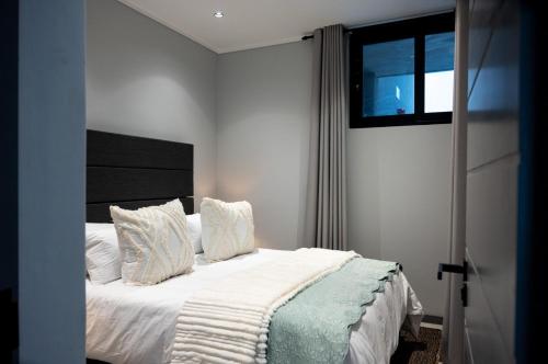 德班Luxury Bellagio 003 One Bed with Inverter的一间卧室配有一张带白色床单的床和一扇窗户。