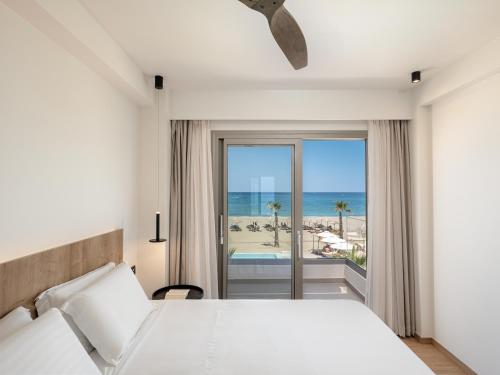 罗希姆诺艾佩里昂海滩酒店的一间卧室配有一张床,享有海滩美景