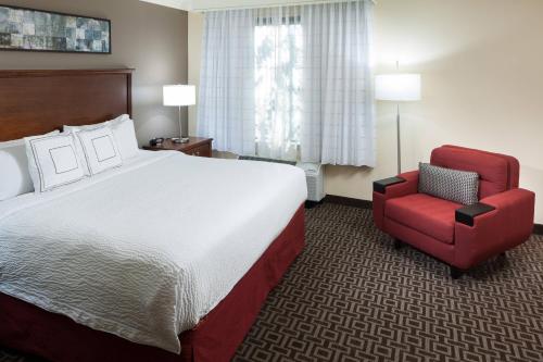 圣安东尼奥圣安东尼奥机场万豪唐普雷斯套房酒店的酒店客房,配有一张床和一张红色椅子