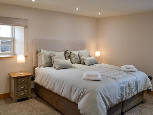 GilcruxGreengill Farm Holiday Cottage - Ukc2768的一间卧室配有一张大床和两条毛巾