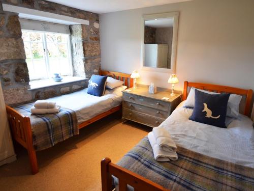 Crowan朗恩谷仓度假屋的一间卧室设有两张床和窗户。