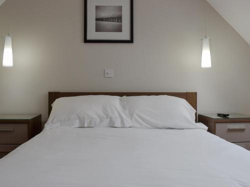 马托克Hollies Cottage 16 - Uck4539的一间卧室配有一张带白色床单和两盏灯的床。