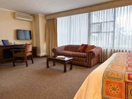 基多La Quinta by Wyndham Quito的带沙发和书桌的酒店客房