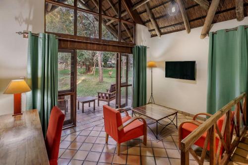 Chisamba普罗蒂亚野生酒店的客厅配有桌椅和电视。