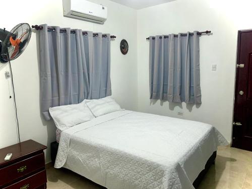 PayitaCasa Linda 10 mins from Beach-Lagoon的卧室配有白色的床和蓝色窗帘