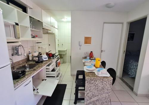 马塞约Quarto e Sala Monte Paradiso的厨房配有白色橱柜和带椅子的柜台。
