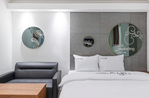 大邱OU Hotel的一间卧室配有一张床、一把椅子和镜子