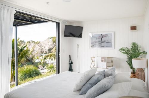 Te AraiAotearoa Surf Eco Pods的白色的卧室设有一张大床和一个大窗户