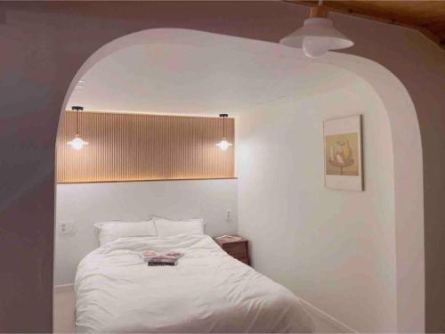 统营市Onheim的卧室配有一张带拱门的白色床