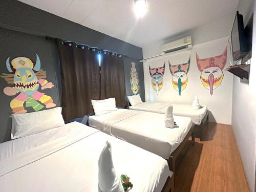 曼谷隐逸曼谷旅舍的一间设有三张床的客房,墙上挂着面具