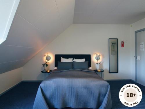 马斯塔尔Ærø Hotel - Adults only的一间卧室配有一张带蓝色床单的床和两盏灯。