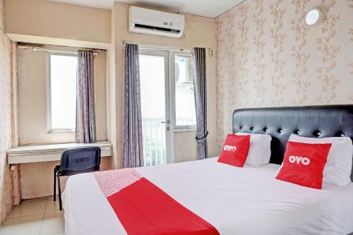 Jaken 1Collection O 92967 Apartement Sentraland Karawang By Rda Living的一间卧室配有一张带两个红色枕头的床