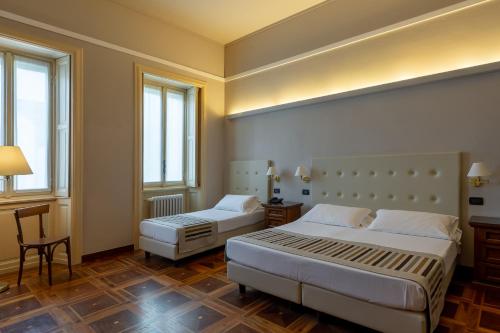 曼托瓦Hotel Antica Dimora的一间卧室设有两张床、一张桌子和两个窗户。