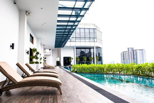 吉隆坡Stay @ NOVO Ampang的酒店游泳池设有躺椅,酒店大楼