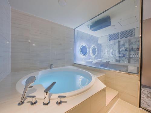 大阪Villa Fontaine Grand Osaka Umeda的带浴缸的浴室和玻璃墙
