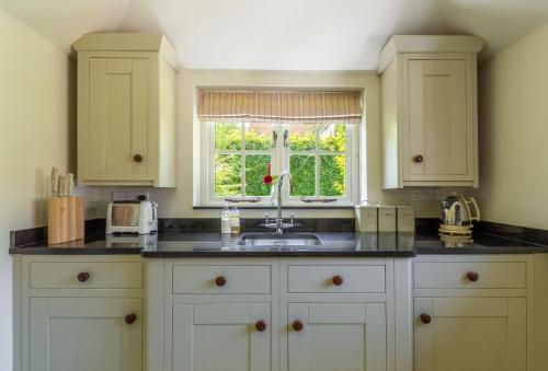 HenfieldHope Cottage - West Sussex的厨房配有白色橱柜、水槽和窗户。