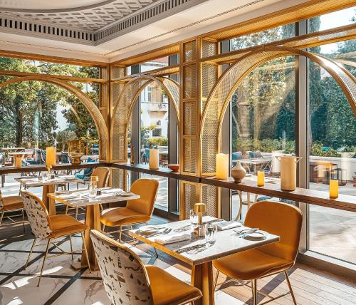 杜布罗夫尼克杜布罗夫尼克希尔顿帝国酒店的餐厅设有桌椅和大窗户。