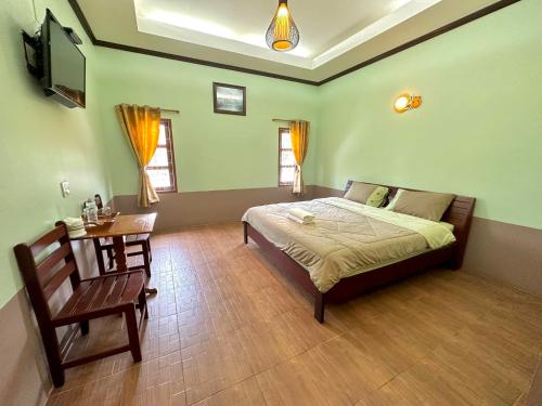 Ban Nam Mongโรงแรมแสงทองรีสอร์ท的一间卧室配有一张床、一张桌子和一台电视