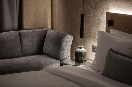 沃洛斯Magnes Hotel的一间卧室配有一张床、一张沙发和一张桌子