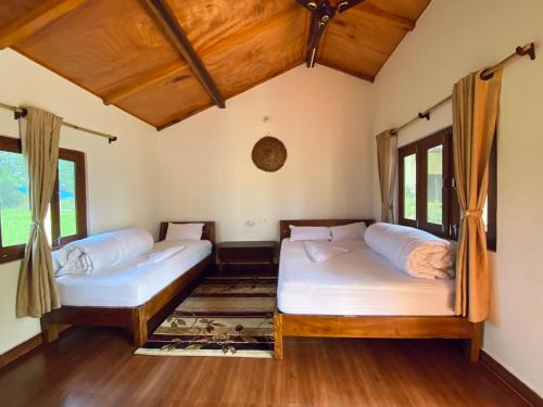BhurkīāBardia Eco Friendly Homestay的客房内设有两张床,铺有木地板,设有窗户。